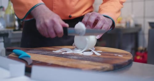 Chef cutting white onion in restaurant kitchen