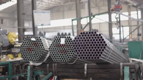 Bundles of Steel Pipes are Moving Along Production Line Inside a Large Industrial Factory