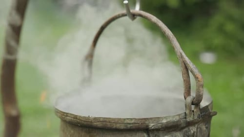 Witch kettle steaming over fire, waving hands with magical spell, slow motion