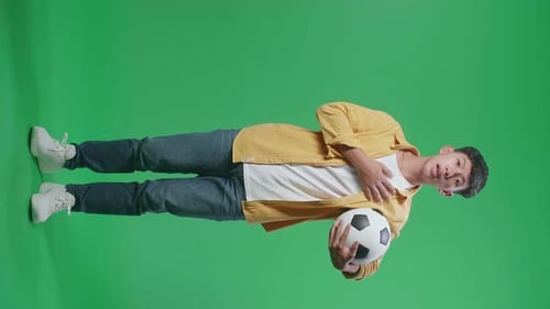 Full Body Of Asian Boy With A Ball Singing National Anthem While Cheering Soccer On Green Screen