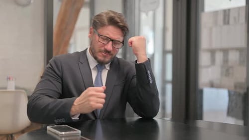 Unsatisfied Mature Adult Businessman Sitting in Office