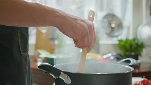Man Stirring Pot in Kitchen