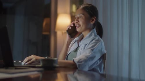 Woman Working at Desk Talking on Phone at Night