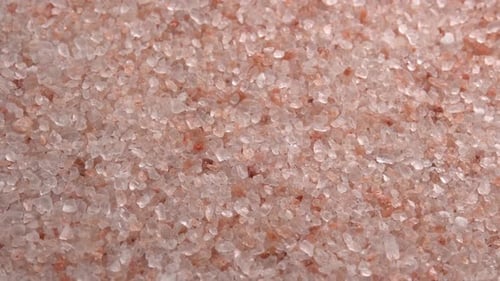 Pink himalayan salt or rock salt rotating close up background top view side light. Trace minerals