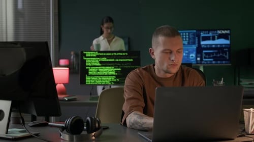 Young Multiethnic Team of IT Specialists Working in Office at Night