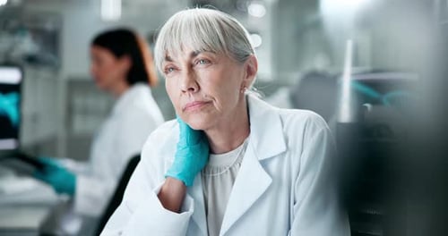 Thoughtful Female Scientist in Lab Wearing Gloves