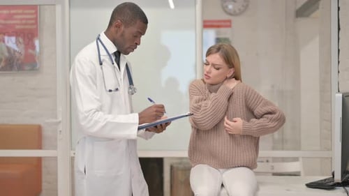 Woman Explaining Pain to Doctor in Medical Office