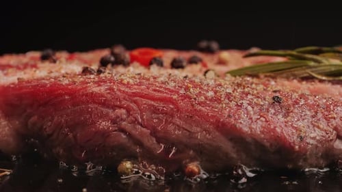 Fresh Marbled Beef with Pepper Salt and Rosemary Closeup Macro Cooking Juicy Steak on Grill with Oil