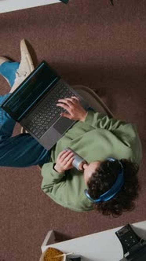 Young Adult Typing on Laptop and Drinking