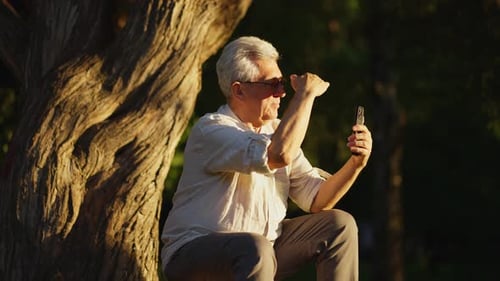 Senior Man Using Smartphone in Golden Sunlight