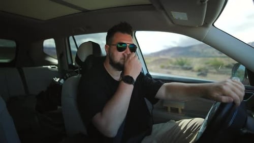 Bärtiger Mann mit Sonnenbrille fährt Geländewagen durch die Wüstenberglandschaft