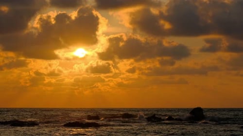 Timelapse of dramatic sunset with orange sky in a cloudy day at a sea shore.