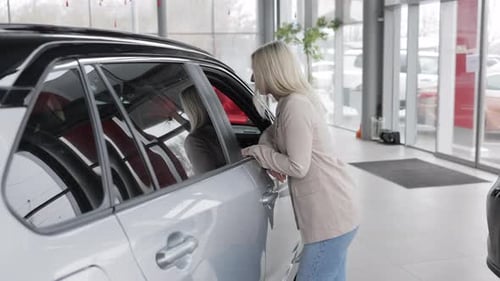 Saleswoman inviting to enter new car in dealership