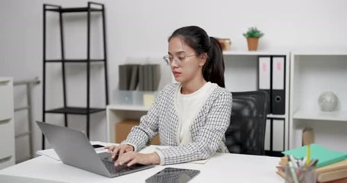 Focused Woman Typing on Laptop in Bright Office