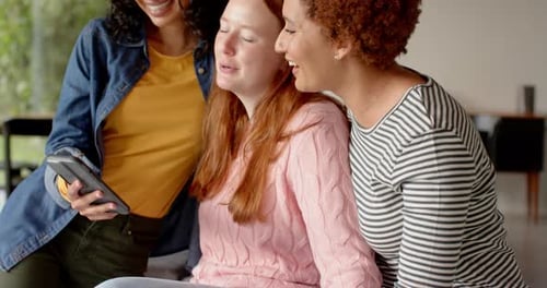 Three Friends Laughing Together at Mobile Phone Indoors