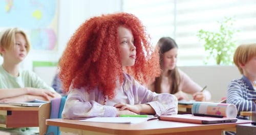 Clever Girl with Red Hair Raising Hand During Lesson at Elementary School Cute Female Student