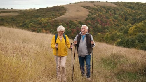 Senior Couple Hiking on Grassy Autumn Hill