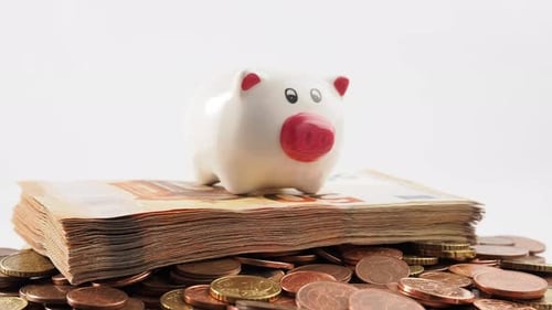 Close-up of rotating metal coins, piggy bank and banknotes. Rotating stack of euro banknotes and eur