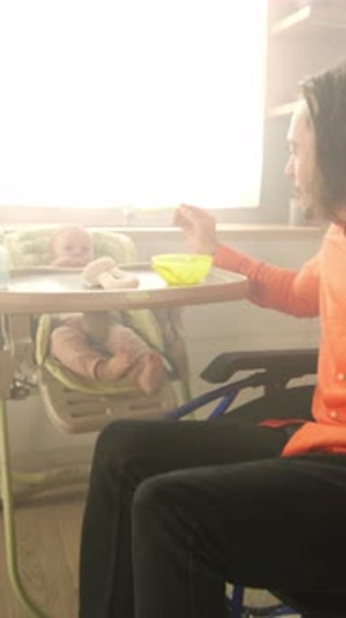 Man Feeding Baby in High Chair at Home