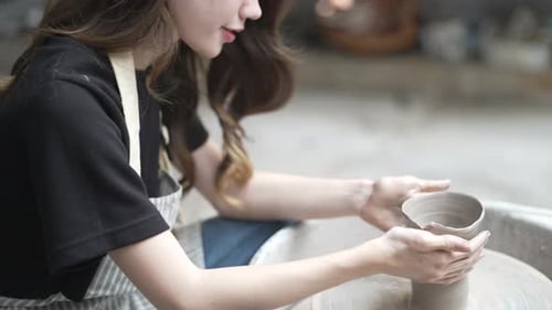 Young women is making earthenware at workshop.