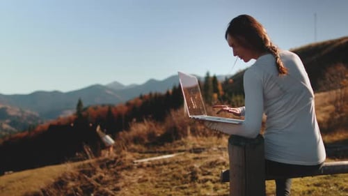 Woman Uses Laptop in Rural Mountainous Environment
