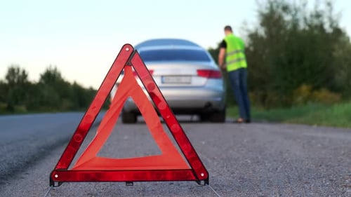 Broken Silver Luxury Car Emergency Accident Man Driver Installing Red Triangle Stop Sign on Road