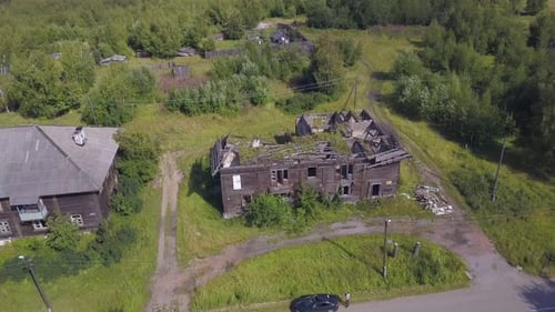 Aerial view of abandoned wooden house in the village among the greenery in summer