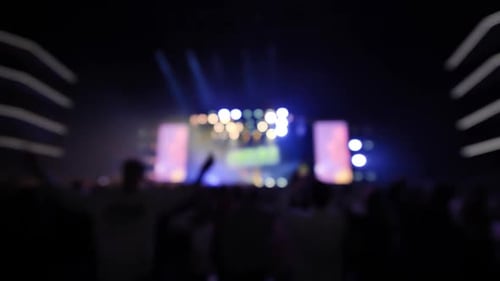 Energetic Crowd at Music Concert with Vibrant Stage Lights