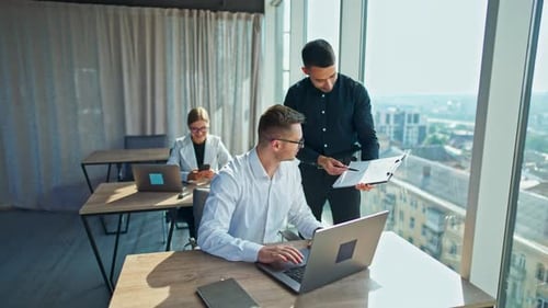 Deux employés de sexe masculin discutent de certaines questions liées au travail et examinent des documents.
