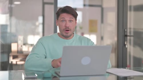 Surprised Man Using Laptop in Bright Office