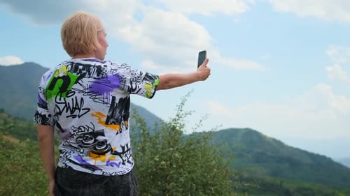 A woman tourist takes photo smartphone selfie against backdrop of breathtaking mountain