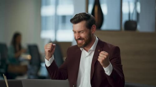 Bearded Man Celebrates Success in Modern Office