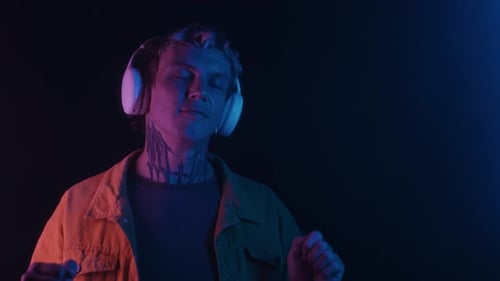 Stylish Man Dancing with Headphones in Neon Lighting