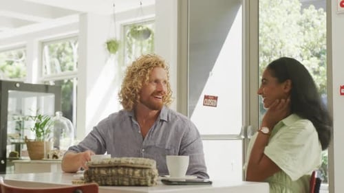 Happy diverse couple drinking coffee and talking at a table in cafe