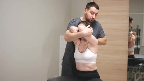 Professional Male Chiropractor Physiotherapist Treating Female Patient in Rehabilitation Center