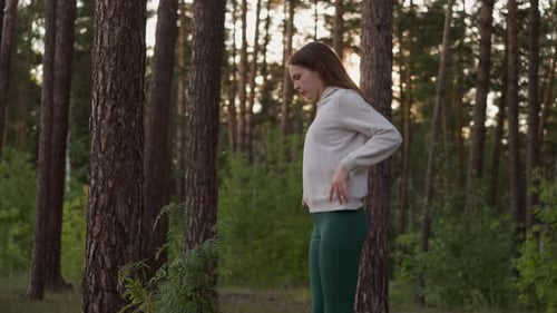 Woman Jumps Exercising in Forest with Trees