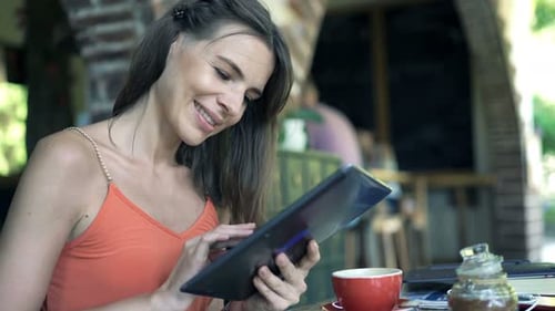 Young, Pretty Woman Using Tablet Computer Sitting by Table in Cafe 30s