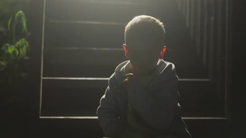 Young Child Sitting Outside at Night on Stairs