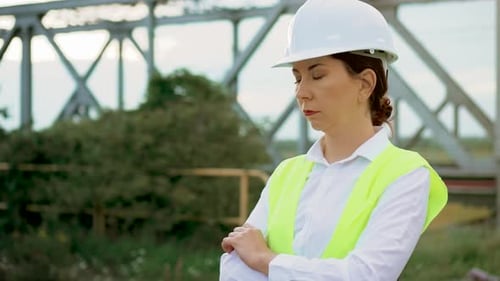 Close Up Portrait of Worker Engineer Woman with Green Vest Near Metal Bridge Construction