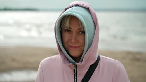 Portrait of a smiling young woman looking at the camera on the shore.