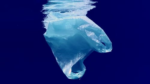 La bolsa de plástico azul claro desechable desechada se desplaza lentamente bajo las olas