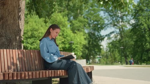Mujer blanca leyendo poesía en voz alta en un banco, voz suave y páginas hojeadas, atmósfera lírica bajo un frondoso paisaje