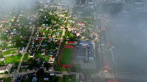 Aerial view of a city seen from the clouds with a stadium at morning