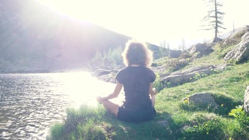 Woman meditating in natural environment on the mountains. One person sitting in lotus pose on rock n