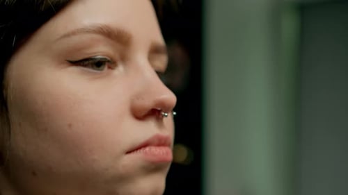Interior de un estudio de piercings: el maestro de piercings hace un piercing para una niña, piercing para el tabique nasal