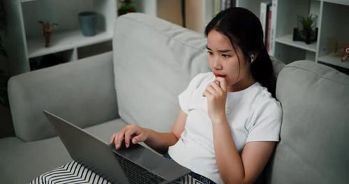 Young Woman Using Laptop on Couch at Home