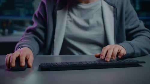 Anonymous Software Developer / Hacker Sitting at His Desk and Typing on Computer Keyboard. Neon Tec