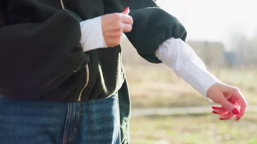 Close Up Adult Woman Adjusting Sleeve of Dark Jacket Outdoors Outdoor Environment