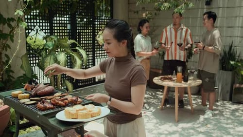Woman Preparing Food on Grill during Barbecue Party with Friends