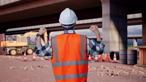 Back View Of A Male Engineer Raising His Hands Celebrating While Working At Building Site